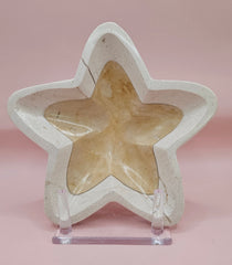Polished onyx star-shaped dish with golden and cream marbling on pink background
