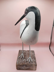 Hand-carved wooden avocet bird sculptures with black and white detailing on rustic stands