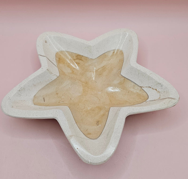 Polished onyx star-shaped dish with golden and cream marbling on pink background