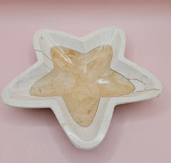 Polished onyx star-shaped dish with golden and cream marbling on pink background