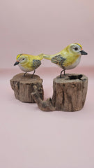 Hand-painted yellow bird figurine on wood stump with pink background – rustic handmade bird decor