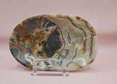 Polished onyx dish with bold black, rust, and cream patterns displayed upright on pink background