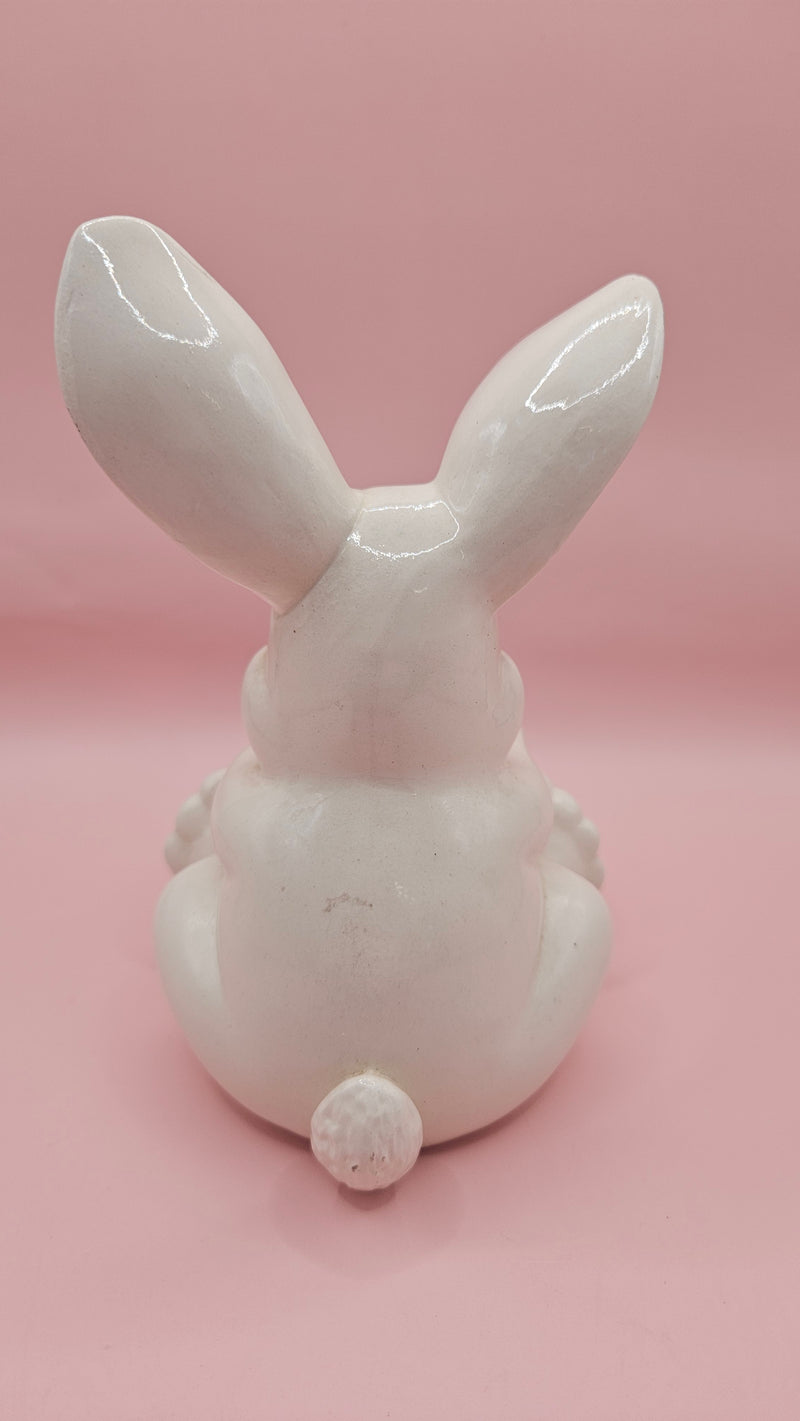 Vintage ceramic bunny rabbit holding a blue egg. 6" hand-painted figurine with pink accents. A charming, pre-loved Easter or spring décor piece.