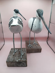 Hand-carved wooden avocet bird sculptures with black and white detailing on rustic stands