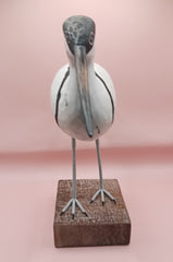 Hand-carved wooden avocet bird sculptures with black and white detailing on rustic stands