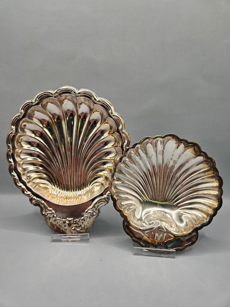 A close-up of two vintage silver-plated scalloped trays, showcasing their reflective finish and elegant, curved edges. Trays come in two sizes, 4.5"x4.25" and 6"x5", perfect for serving or decorative use