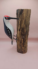 Three individual hand-painted woodpecker figures mounted on varying pieces of natural wood displayed on a teal tabletop.