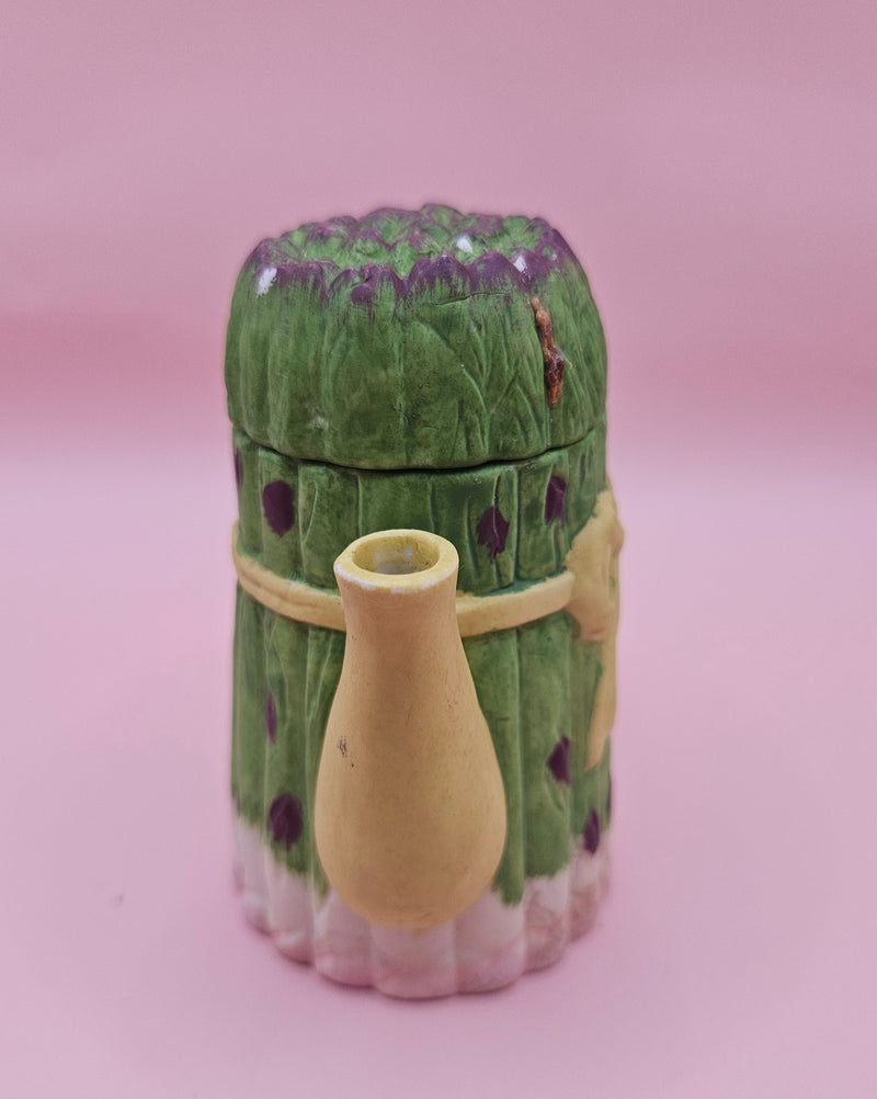 Vintage ceramic miniature teapot shaped like asparagus stalks with purple tips and a yellow ribbon bow, approximately 3.6 inches tall.