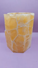 Honeycomb calcite candle cover with translucent golden tones and a hexagonal shape, measuring 6.75x5.5 inches.