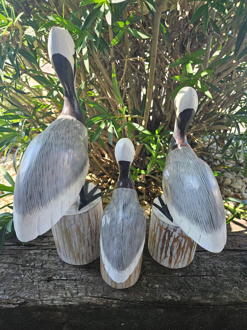 Carved wooden pelican decor in three sizes, small (11.5 x 7 inches), medium (14 x 9.5 inches), and large (17.75 x 11 inches), perfect for coastal decor