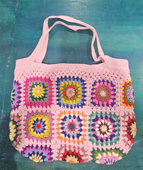 colorful handmade crochet tote bags with granny square designs in pink and black, tan and blue backgrounds, displayed on a teal surface