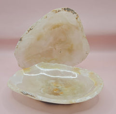 Creamy raw-edge onyx dish with soft golden veining and irregular shape on pink background