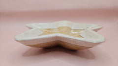 Polished onyx star-shaped dish with golden and cream marbling on pink background