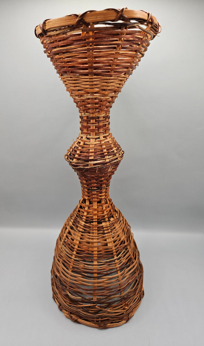 A 12.5" vintage woven wicker rattan vase basket with an hourglass shape, handcrafted from natural rattan, perfect for rustic or boho decor.