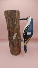 Three individual hand-painted woodpecker figures mounted on varying pieces of natural wood displayed on a teal tabletop.