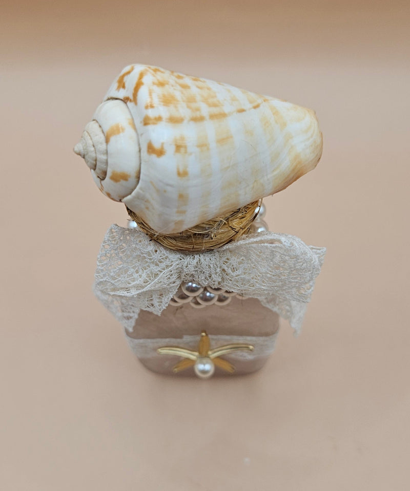 Vintage 5.5"x2" decorative bottle with a spiral seashell top, lace bow, pearl accents, and gold starfish charm against a neutral background