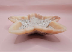 Light pink and ivory polished onyx star-shaped dish with natural veining on pink background