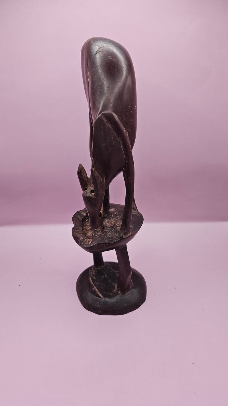 Vintage hand-carved wooden antelope sculpture, measuring 11"x3.5", featuring intricate details on a pink background.