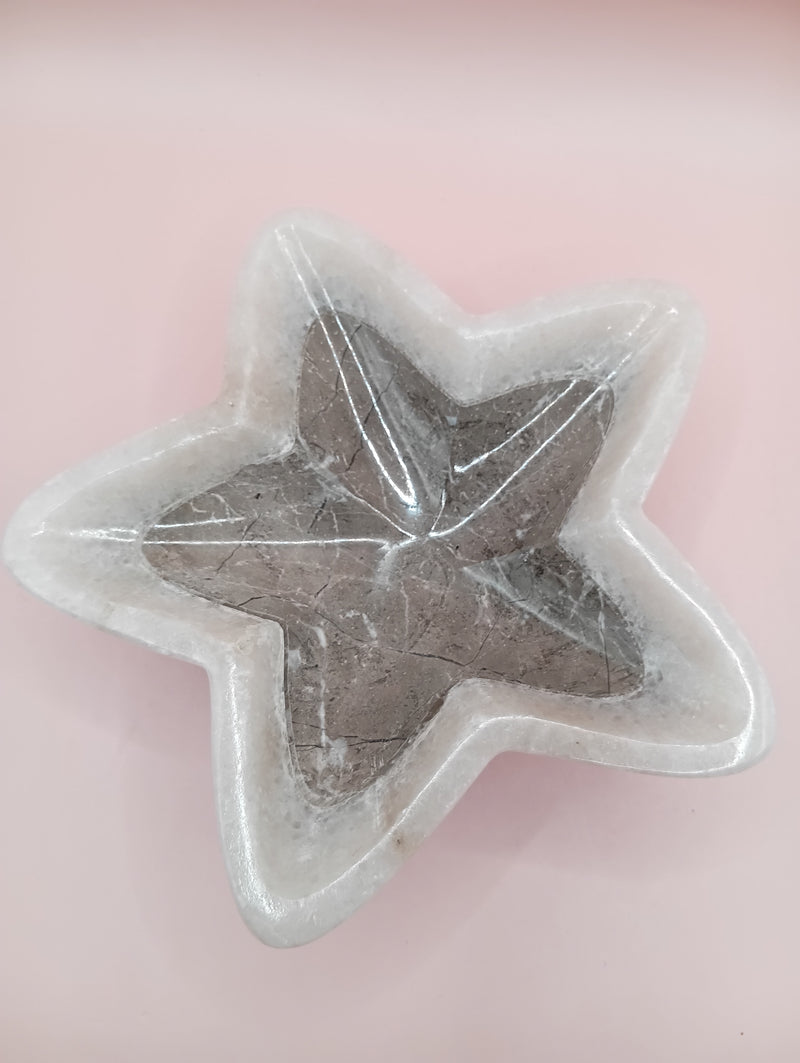 Three hand-carved onyx star bowls in brown, beige, and grey displayed vertically on a black surface