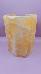 Honeycomb calcite candle cover with translucent golden tones and a hexagonal shape, measuring 6.75x5.5 inches.