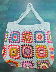 colorful handmade crochet tote bags with granny square designs in pink and black, tan and blue backgrounds, displayed on a teal surface