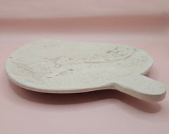 Leaf-shaped fossil marble shallow dish with subtle imprints, shown on a pale pink background.