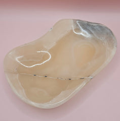 Polished onyx dish with cream and charcoal veining on pink background