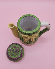 Vintage ceramic miniature teapot shaped like asparagus stalks with purple tips and a yellow ribbon bow, approximately 3.6 inches tall.