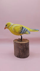Hand-painted yellow bird figurine on wood stump with pink background – folk art decor