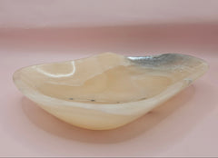Polished onyx dish with cream and charcoal veining on pink background
