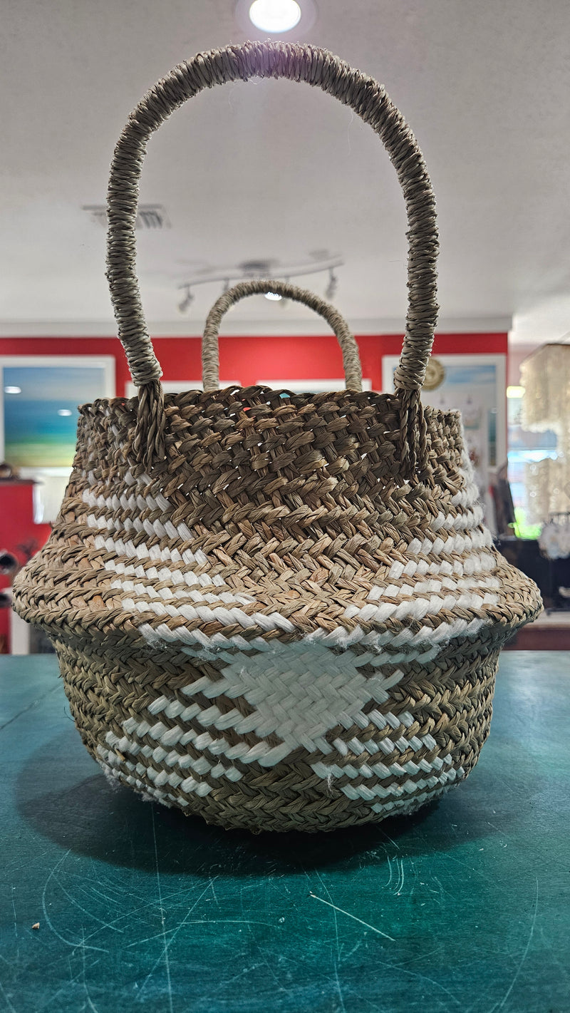 Handwoven seagrass belly basket with white diamond pattern and handles, 11.5x9.5 size on display