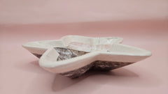 Dark polished onyx star dish with gray and brown veining on pink background