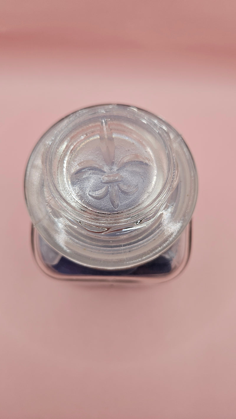 Vintage glass jar with cobalt and frosted sea glass, floral lid detail, ocean-inspired coastal decor on pink background