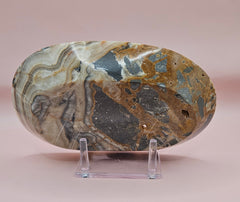 Polished onyx dish with bold black, rust, and cream patterns displayed upright on pink background