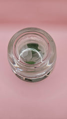Apothecary glass jar filled with aqua and green sea glass and pottery shards, coastal decor accent on pink background