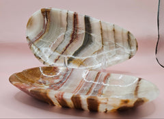 Oval onyx dish with bold natural stripes in tan, cream, and rust on pink background