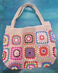 colorful handmade crochet tote bags with granny square designs in pink and black, tan and blue backgrounds, displayed on a teal surface