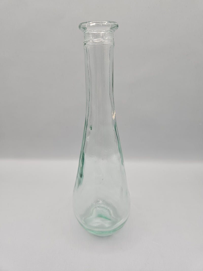 Vintage teardrop-shaped glass bottle, 7 inches tall by 2 inches wide, clear glass, perfect for décor or as a small vase.