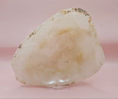 Creamy raw-edge onyx dish with soft golden veining and irregular shape on pink background