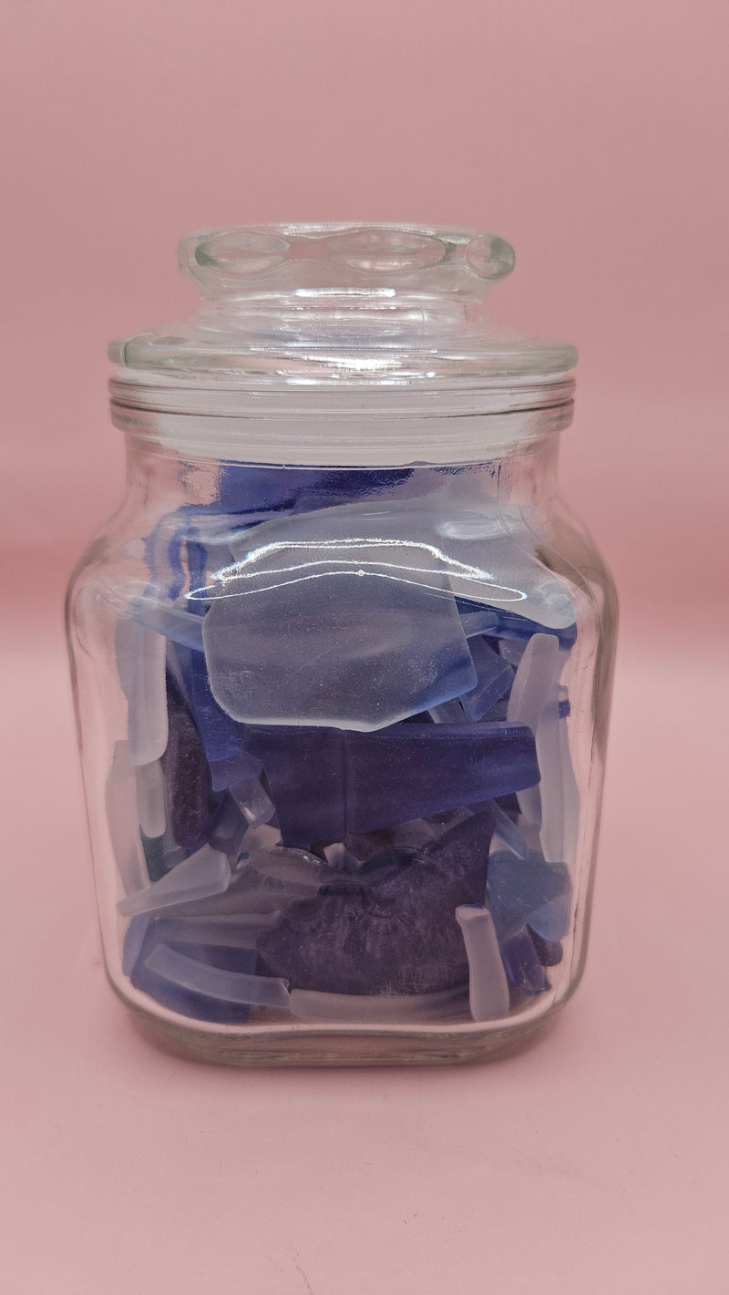 Vintage glass jar with cobalt and frosted sea glass, floral lid detail, ocean-inspired coastal decor on pink background