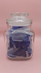 Vintage glass jar with cobalt and frosted sea glass, floral lid detail, ocean-inspired coastal decor on pink background