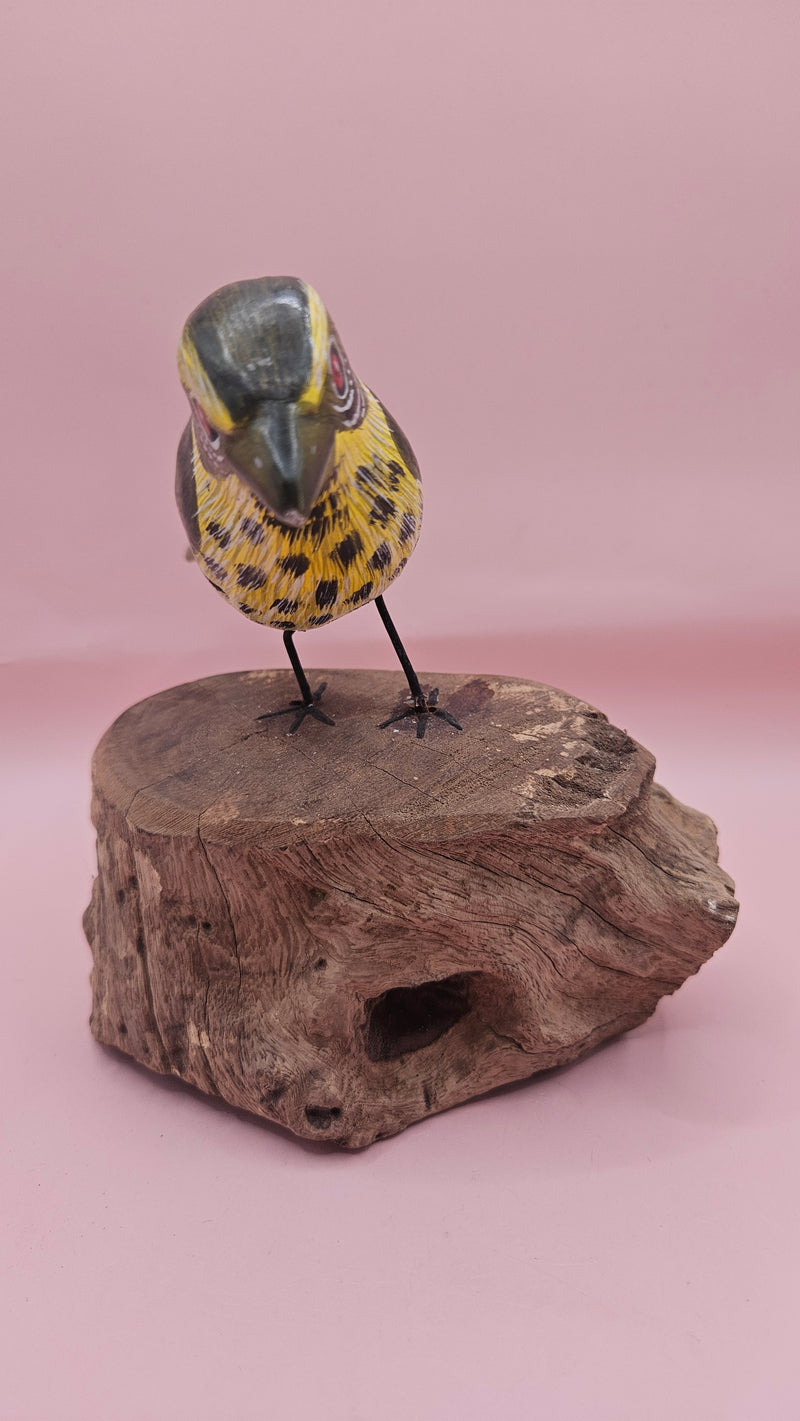 Handmade green songbird figurine with yellow and brown details, perched on a natural wood stump, 5x4 inches.