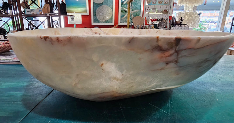 Large hand-carved onyx stone bowl with polished finish and creamy marbled tones in white, amber, and rose.