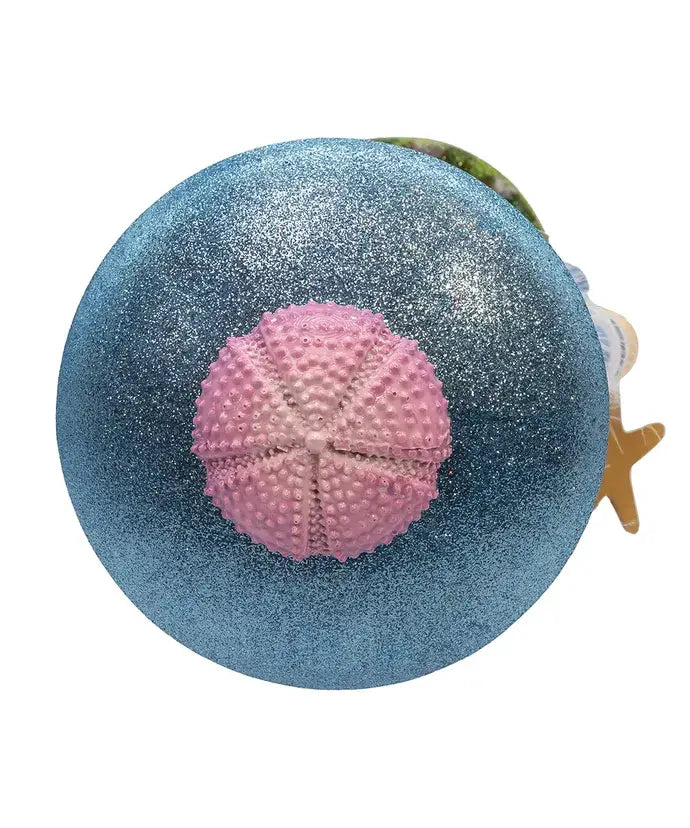 Decorative item with a blue glittery sphere and pink sea urchin on a white background