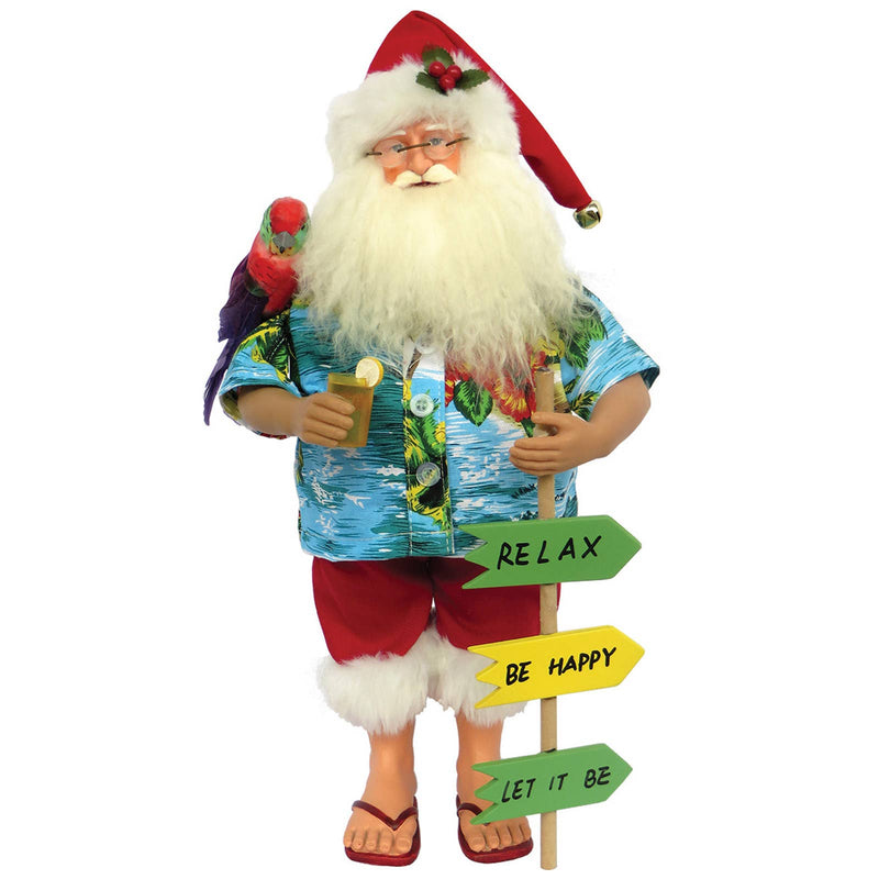 A 15-inch figurine of Santa Claus wearing a blue Hawaiian shirt and red dungarels with a white faux fur trim, holding a drink and with a parrot on his shoulder. He stands on a sandy surface with a sign that has three arrows pointing to 'Relax', 'Be Happy', and 'Let It Be'.